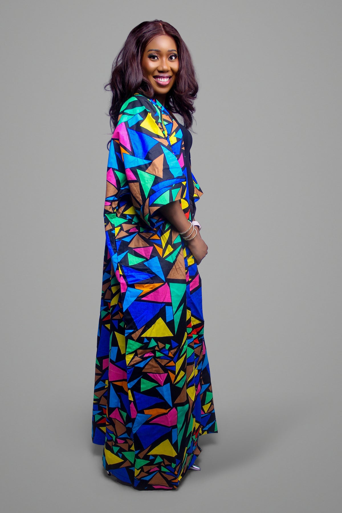 Side profile of a woman wearing a floor-length kimono with a vibrant multi-colored geometric mosaic pattern
