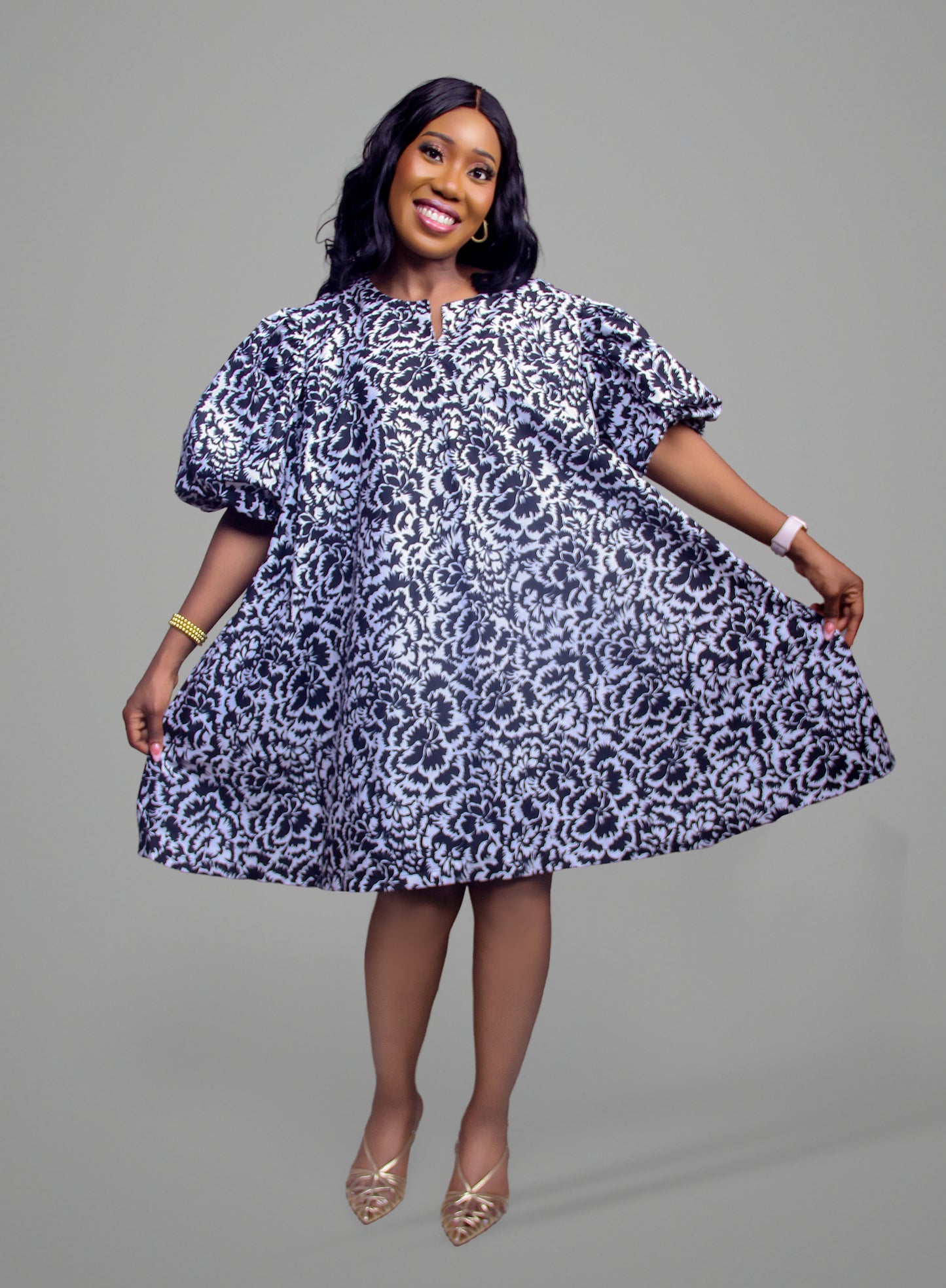 A woman wearing a black and white floral damask dress with dramatic puff sleeves and a flared skirt