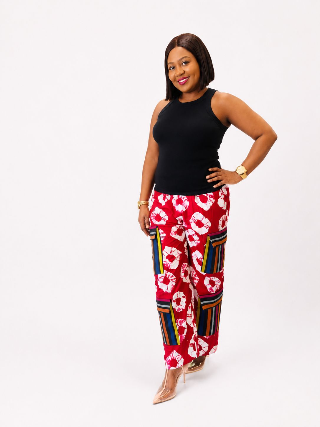 Side profile view of red tie-dye wide-leg cargo pants with hand on hip.