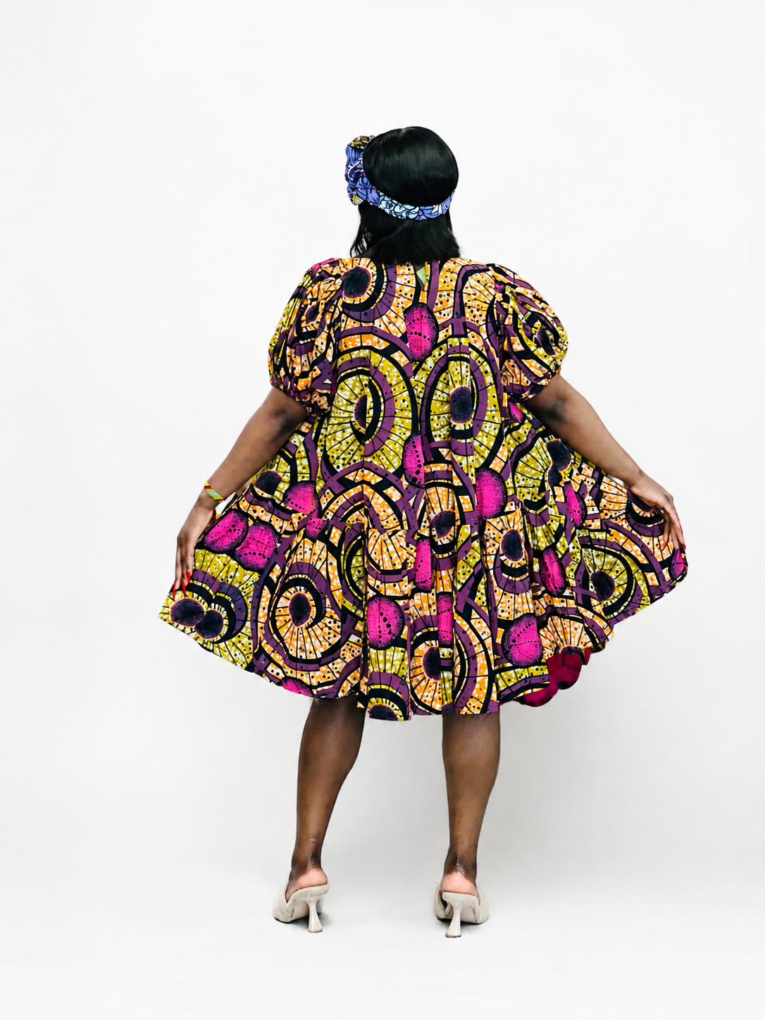 Back view of a yellow and purple geometric print mini dress with tiered hem.