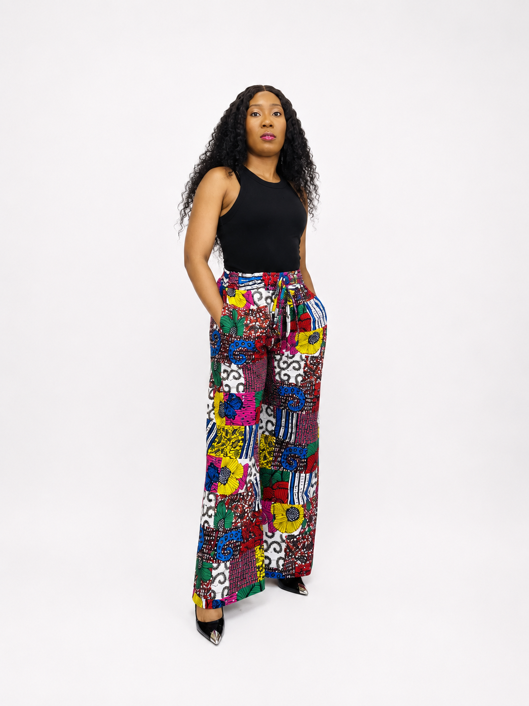 A full-length front view of multicoloured Ankara print wide-leg trousers with a drawstring waist.