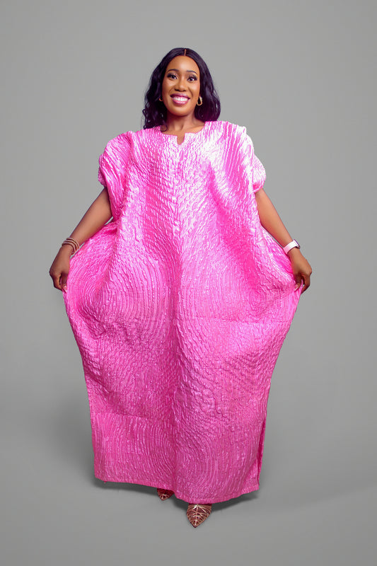 A full-length view of a vibrant pink bubu kaftan featuring an embossed, textured finish on a person.