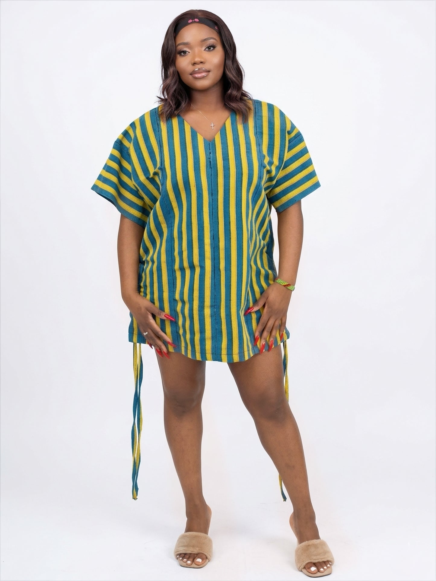 A person wearing a yellow and blue striped V-neck tunic with hanging side ties and short sleeves.