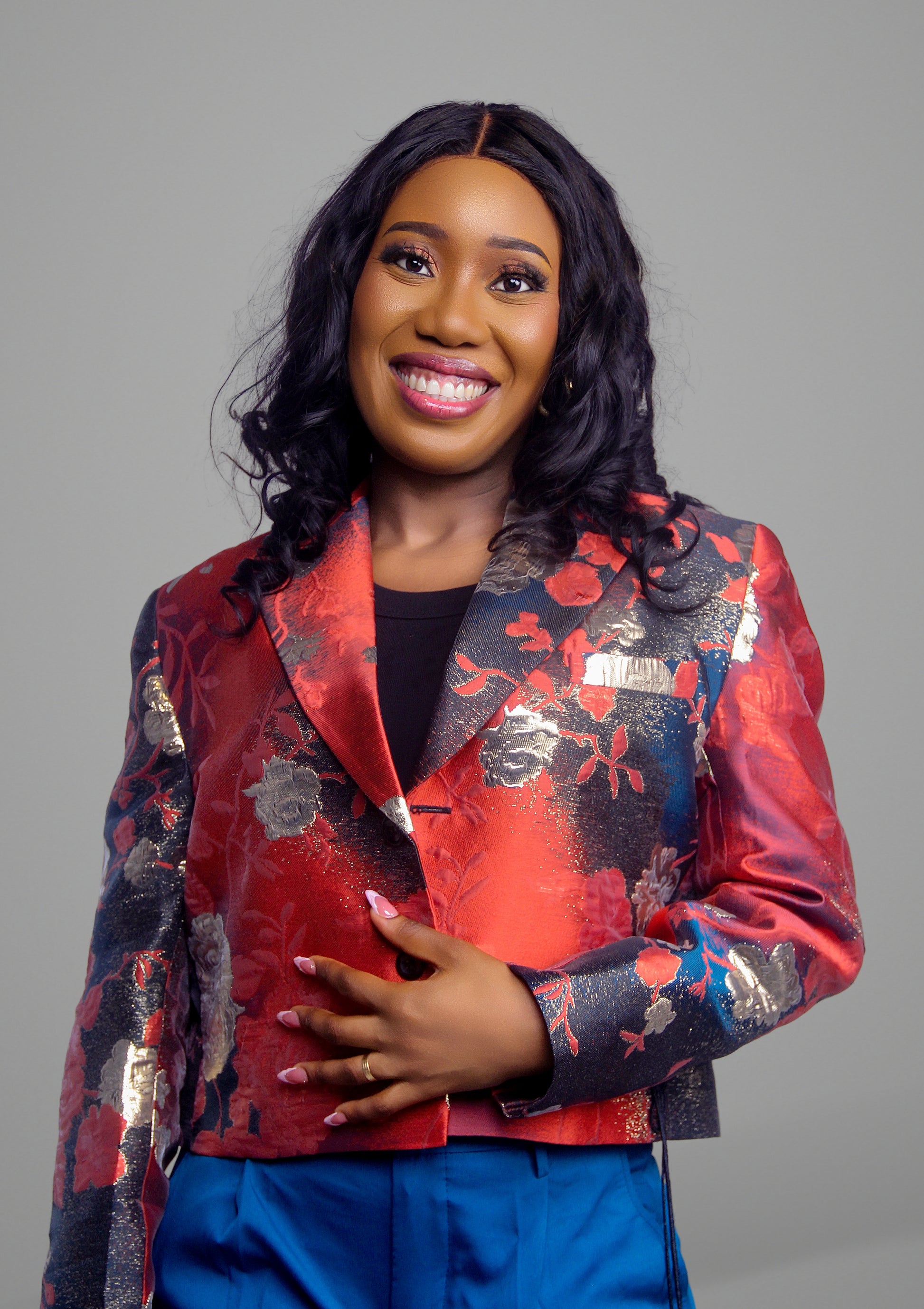 Close up portrait of woman wearing a red floral brocade blazer