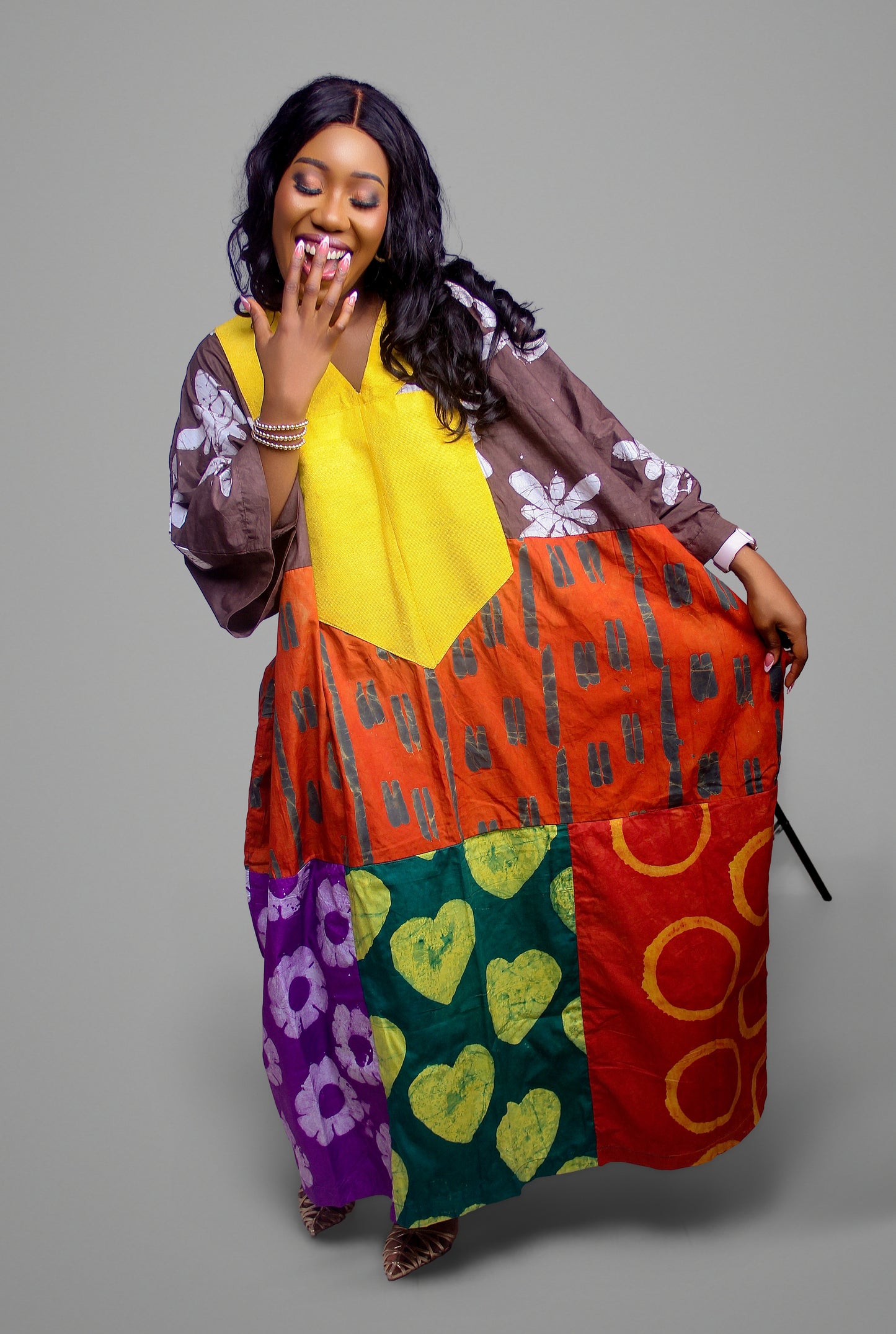 Kaftan dress displaying a yellow chest panel with a patchwork skirt featuring heart, floral, and circular batik patterns.