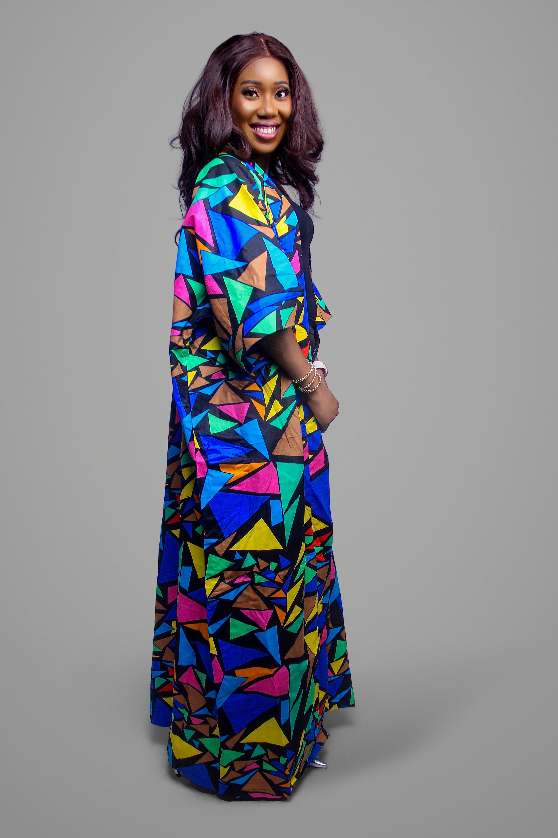 Side profile of a woman wearing a floor-length kimono with a vibrant multi-colored geometric mosaic pattern