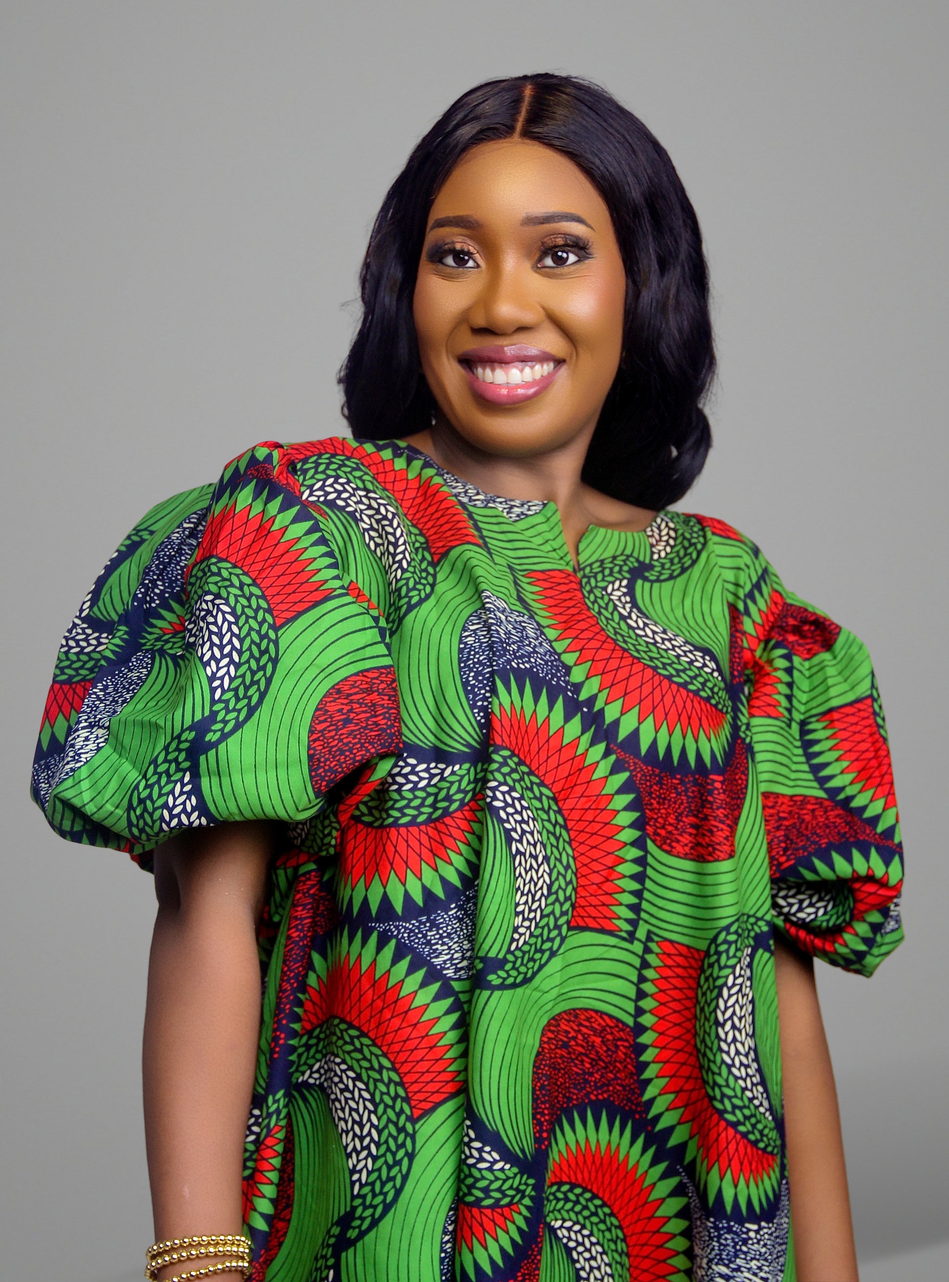Front view of a vibrant green, red, and black patterned Ankara print dress with voluminous puff sleeves