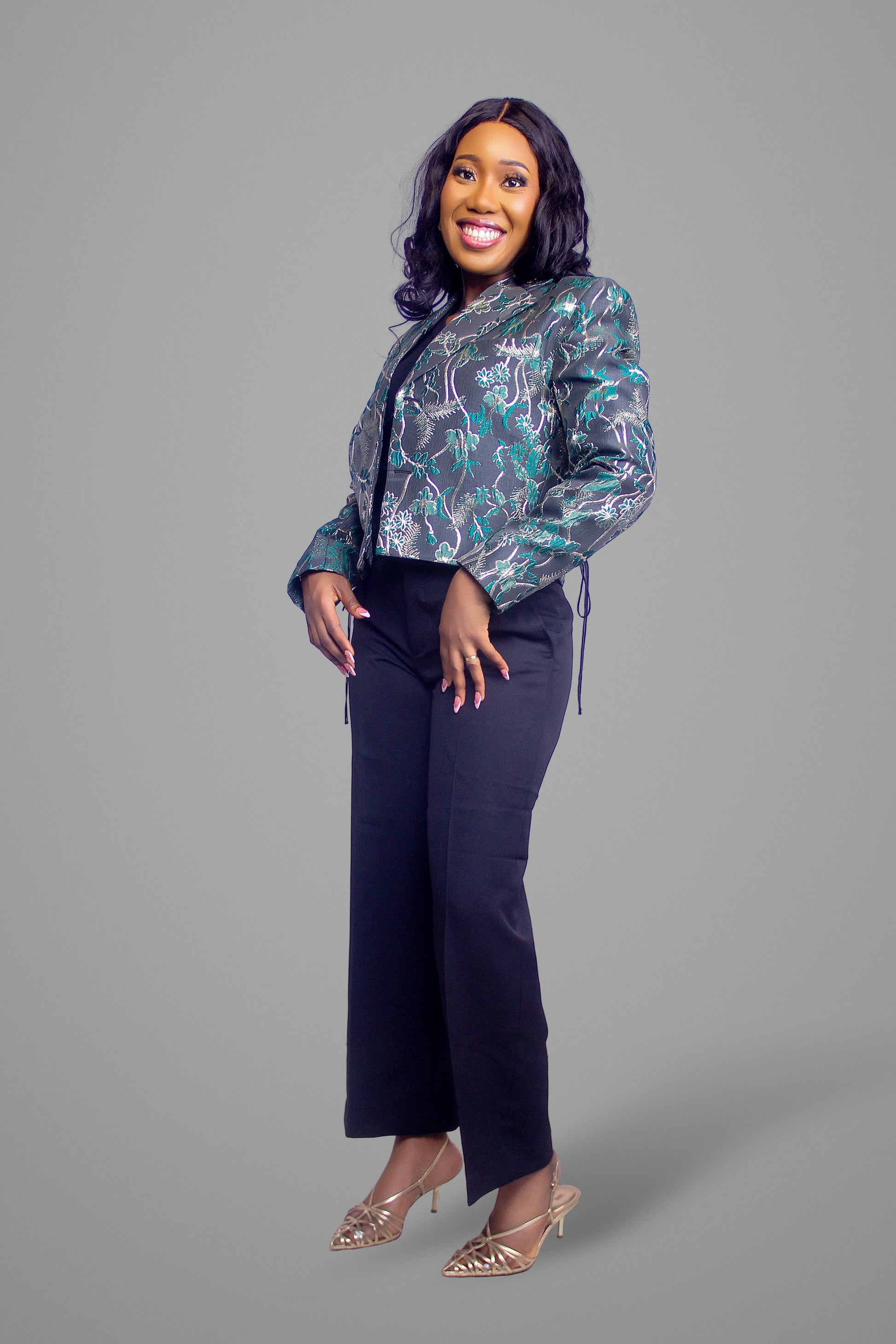 Side view of woman wearing a cropped green and grey floral brocade blazer