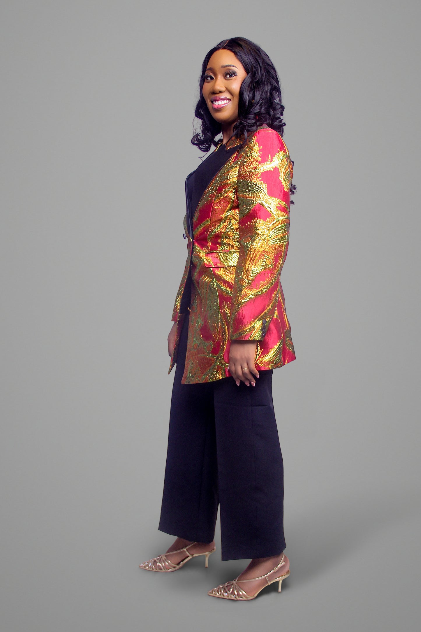 Full body view of woman in a cropped gold and red floral brocade blazer