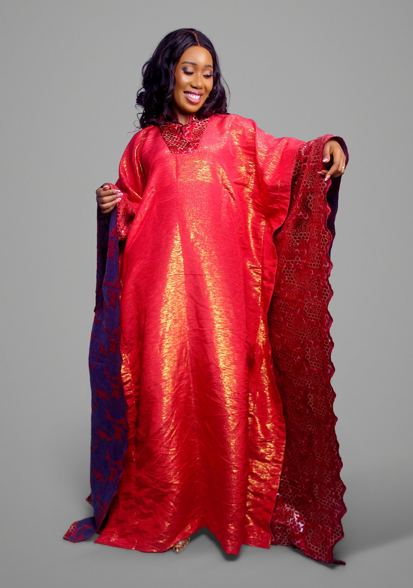 A vibrant red kaftan dress with metallic sheen and dark contrast accents.