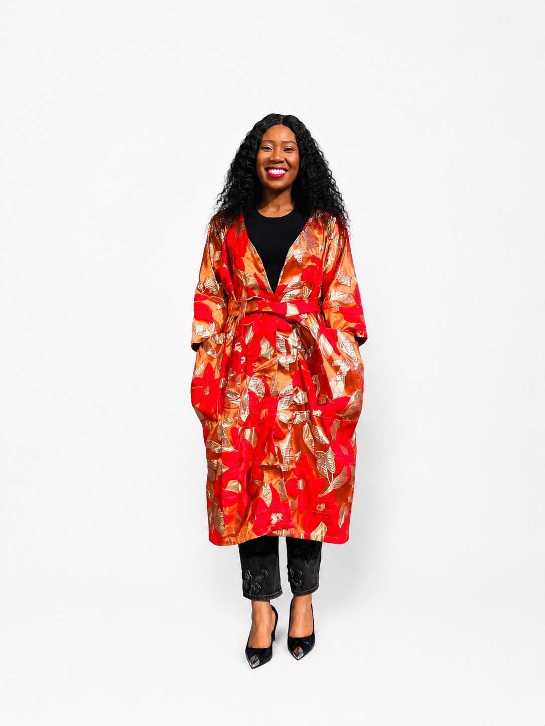 Front view of a woman wearing a red and gold floral brocade kimono coat with a tie waist.