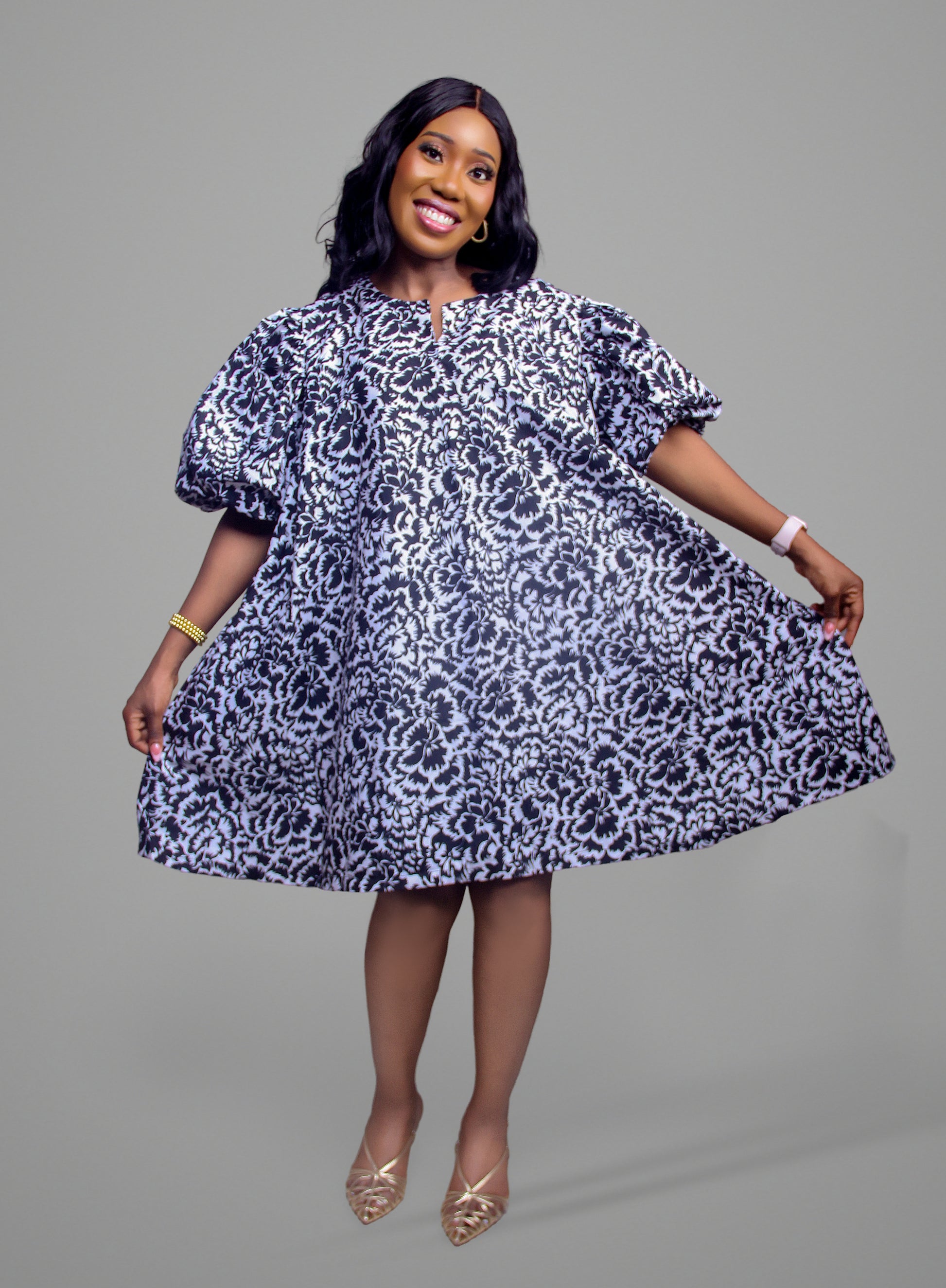 A woman wearing a black and white floral damask dress with dramatic puff sleeves and a flared skirt