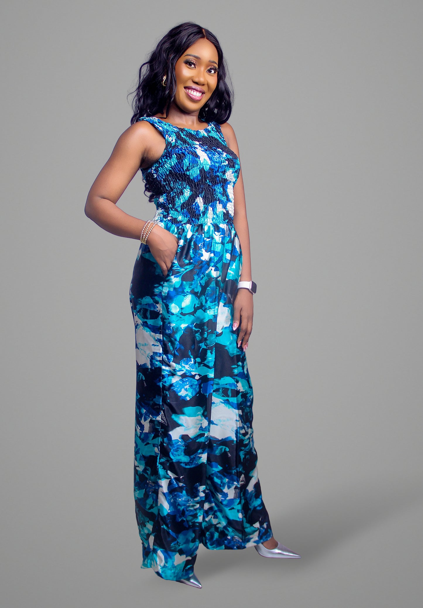 A full-body view of a blue abstract print jumpsuit with a smocked bodice and wide legs.