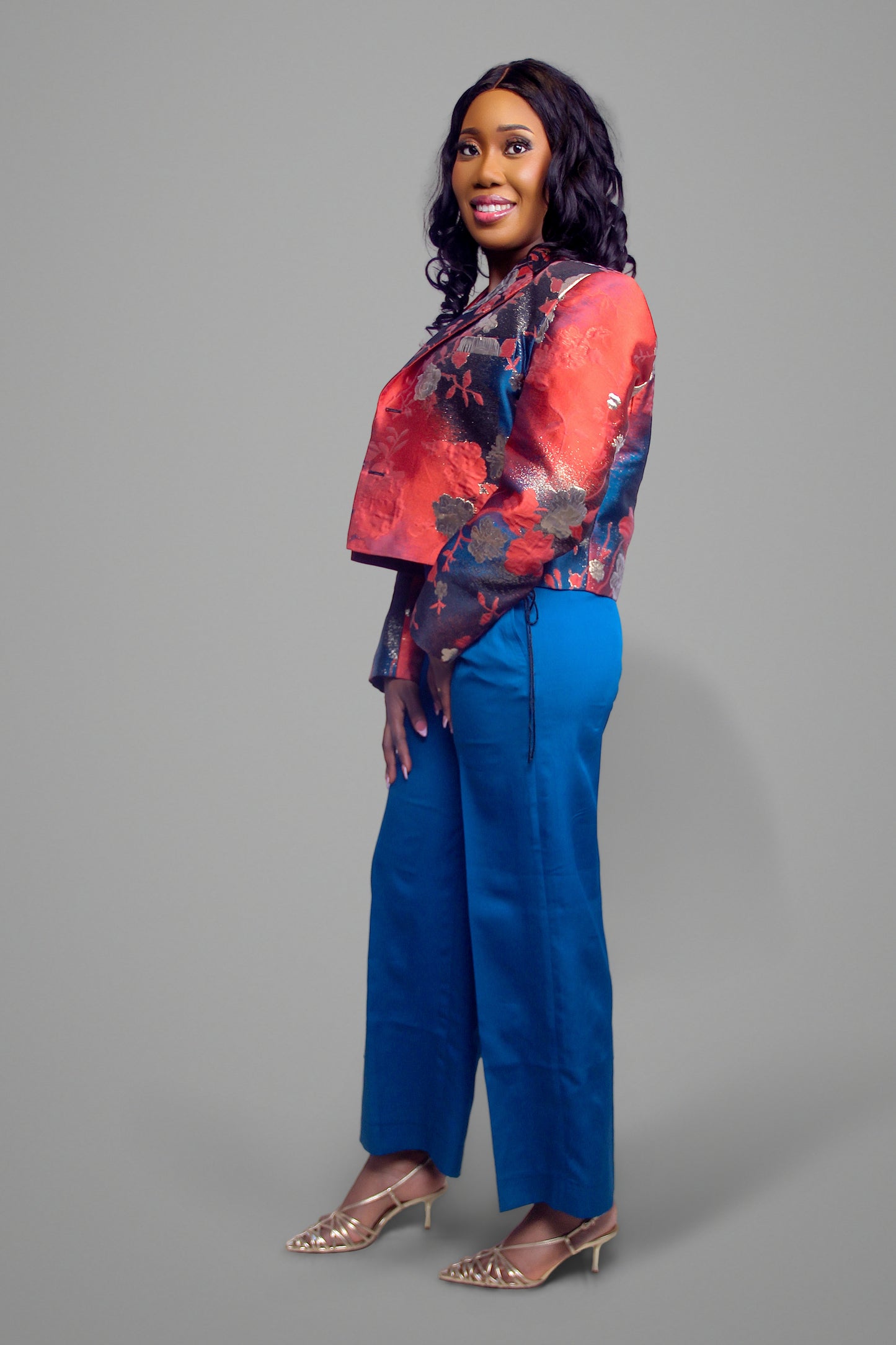 Side view of woman wearing a cropped red floral brocade blazer