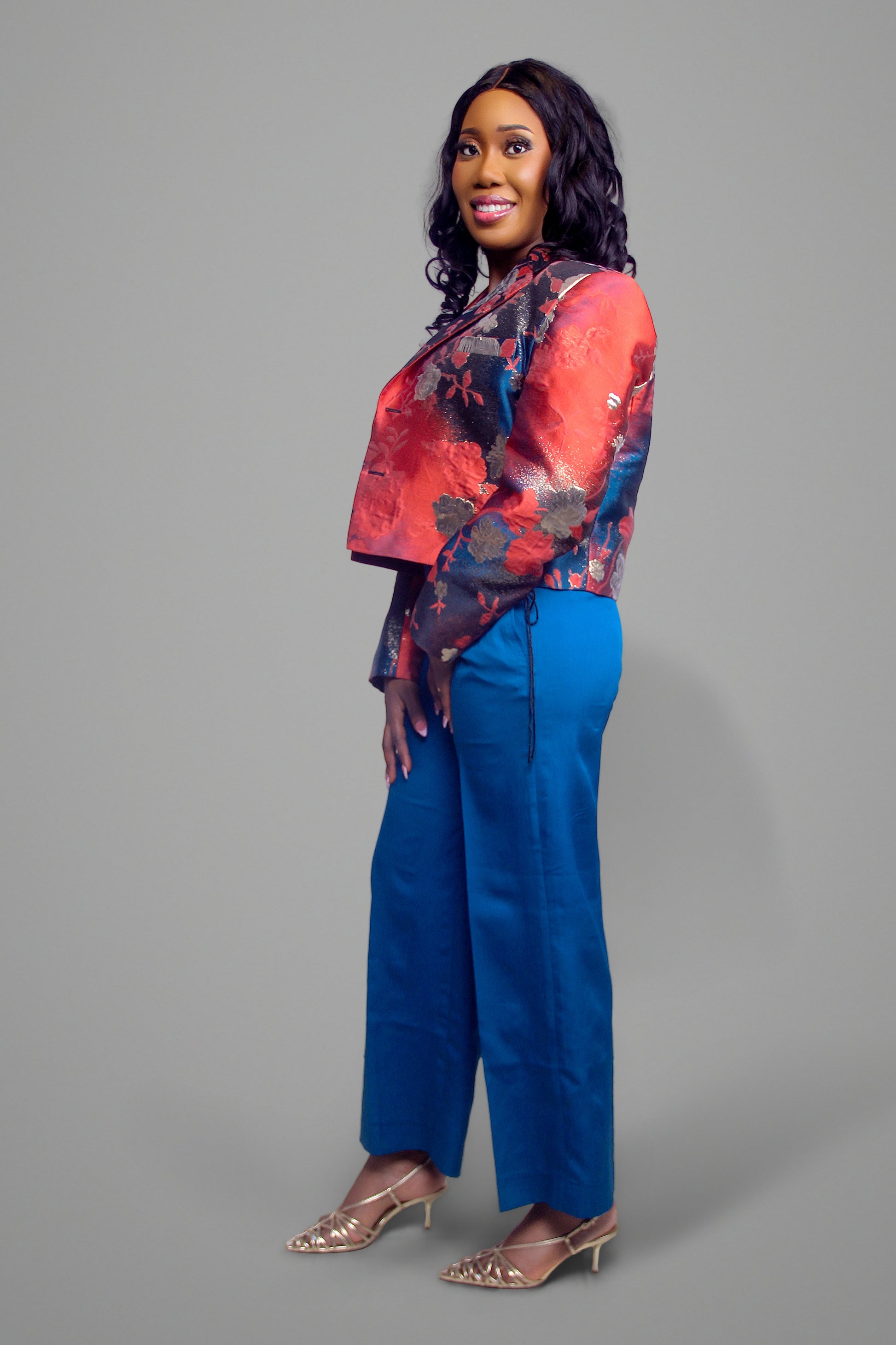 Side view of woman wearing a cropped red floral brocade blazer