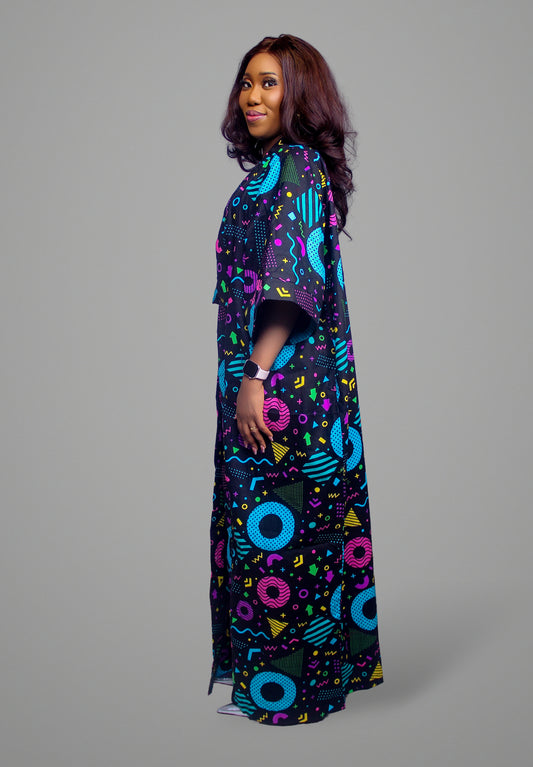 A side view of a floor-length maxi kaftan featuring a bold black, blue, pink, and yellow Memphis-style geometric print on 100% cotton fabric.