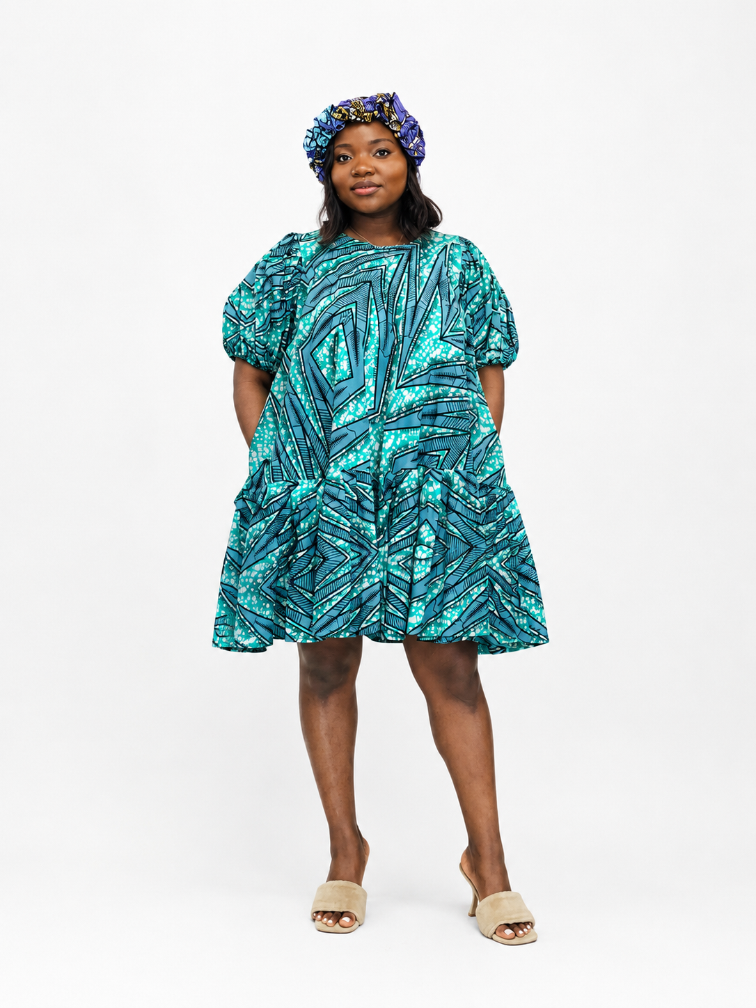 Front view of a tiered babydoll mini dress with a turquoise and geometric print.