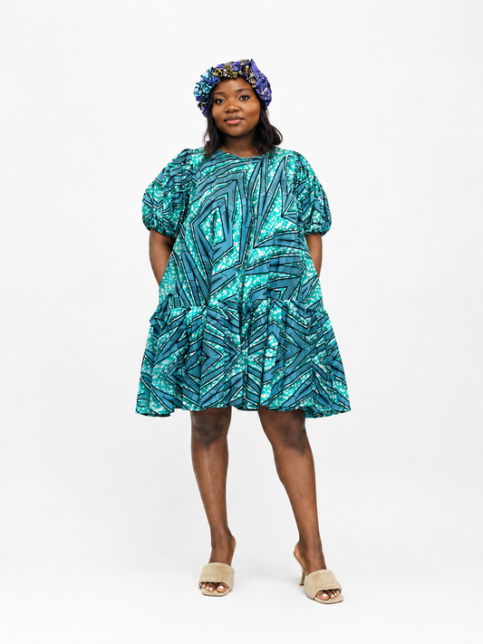 Front view of a tiered babydoll mini dress with a turquoise and geometric print.