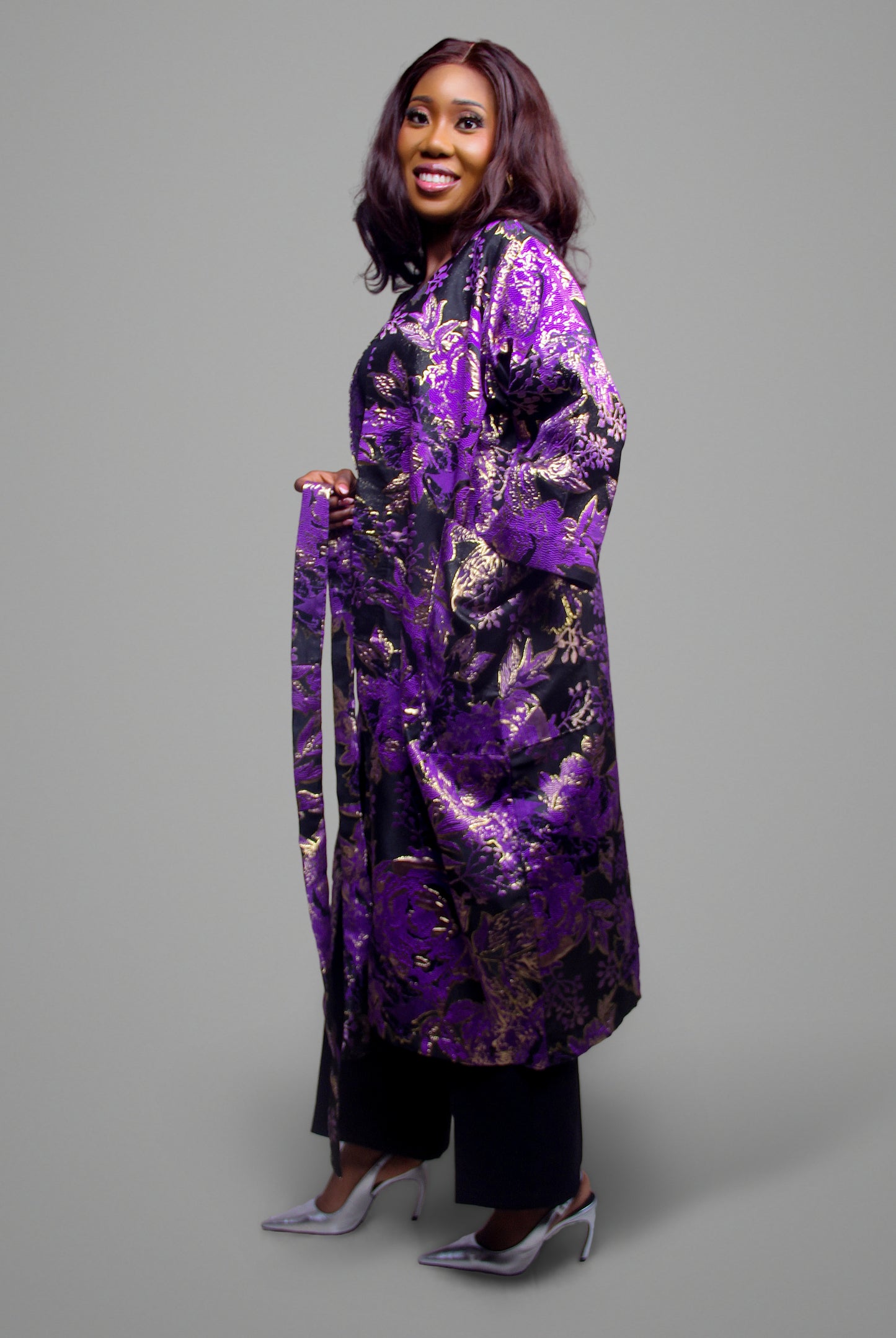 Side profile of a woman wearing a purple and gold floral brocade kimono coat.