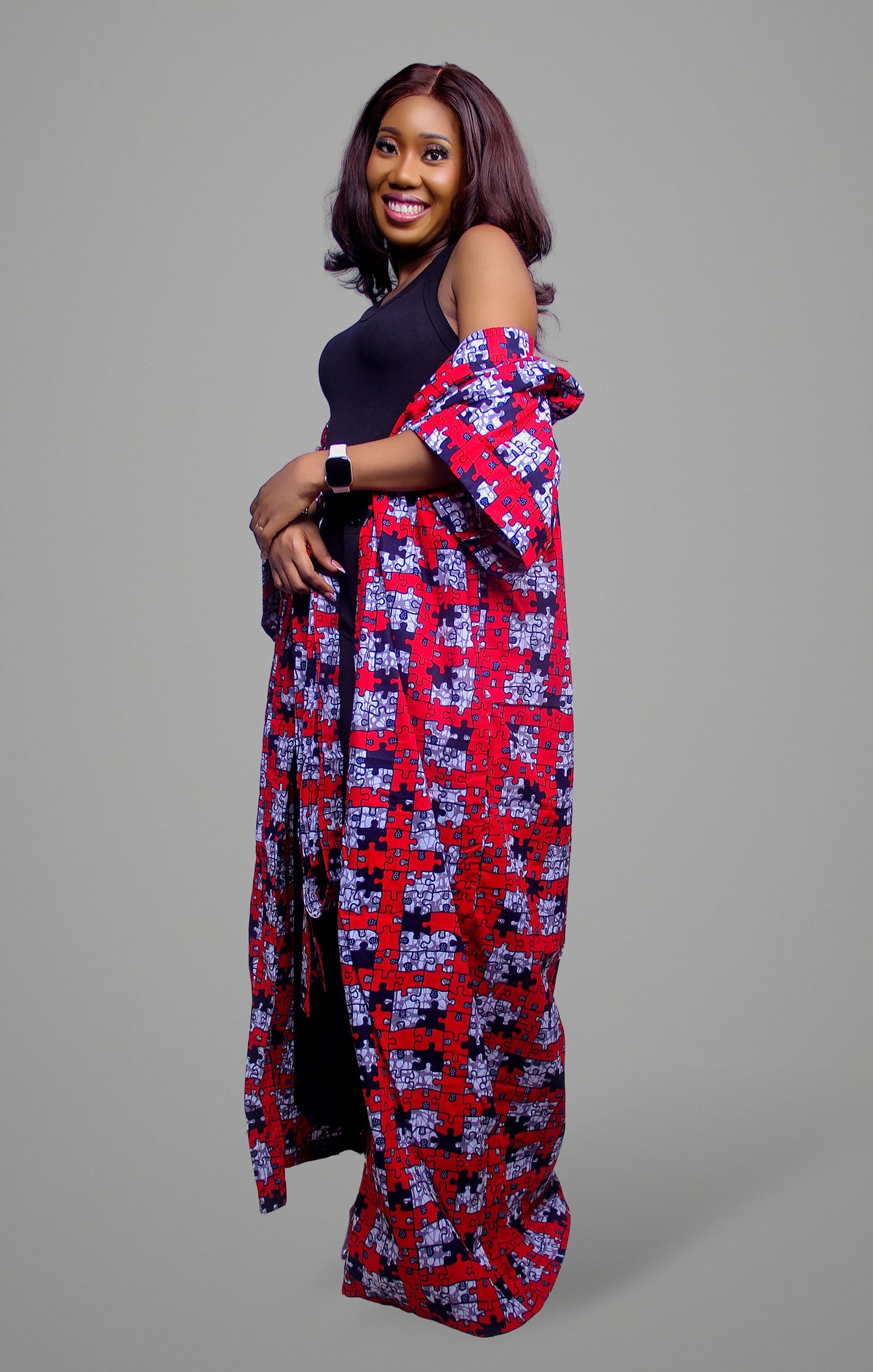 Side profile of a woman wearing a long kimono featuring a distinct red, white, and black interlocking puzzle print